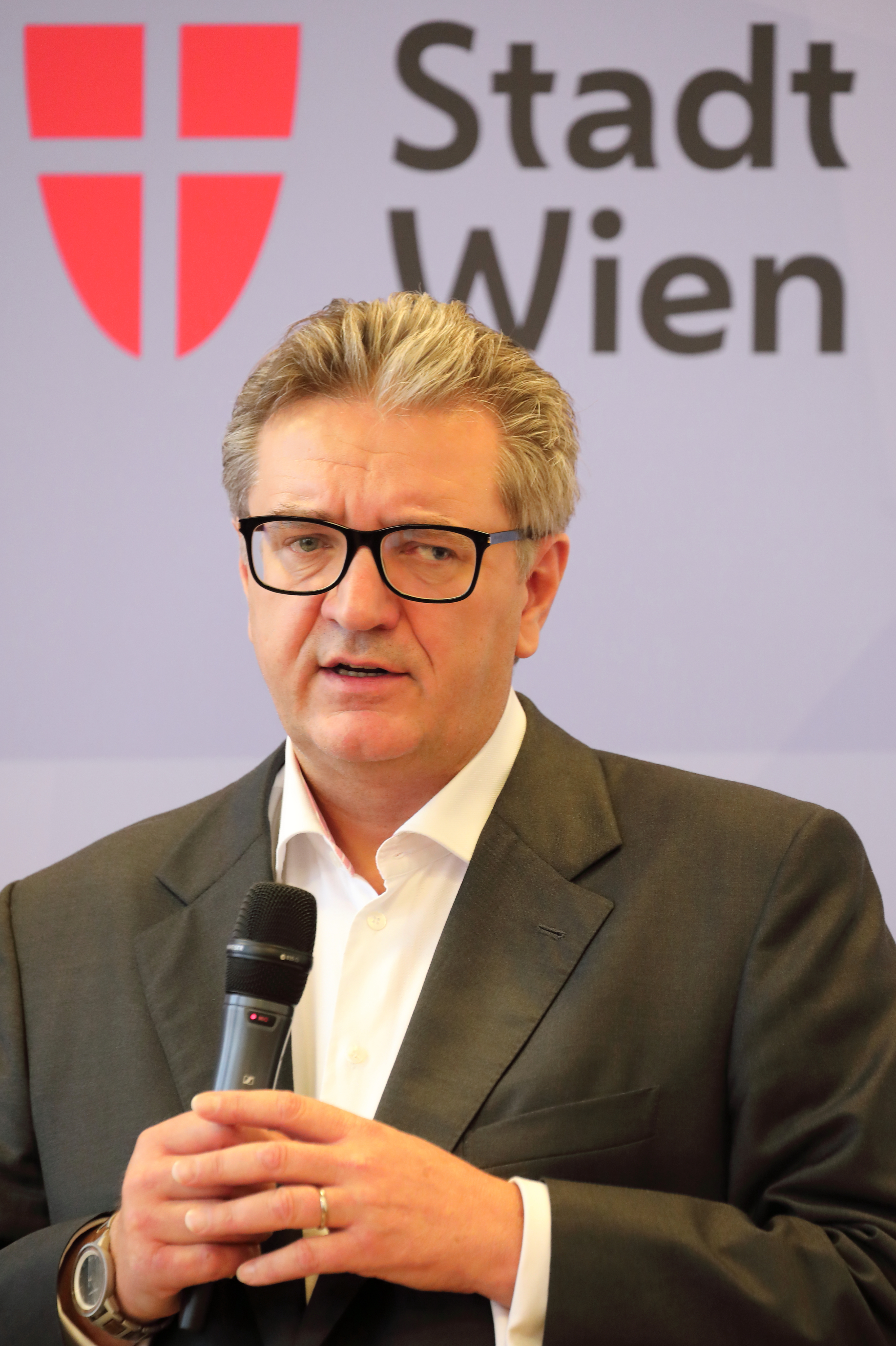 Peter Hacker hält bei einer Pressekonferenz im Wiener Rathaus ein Mikrofon. Archivaufnahme von 2020.