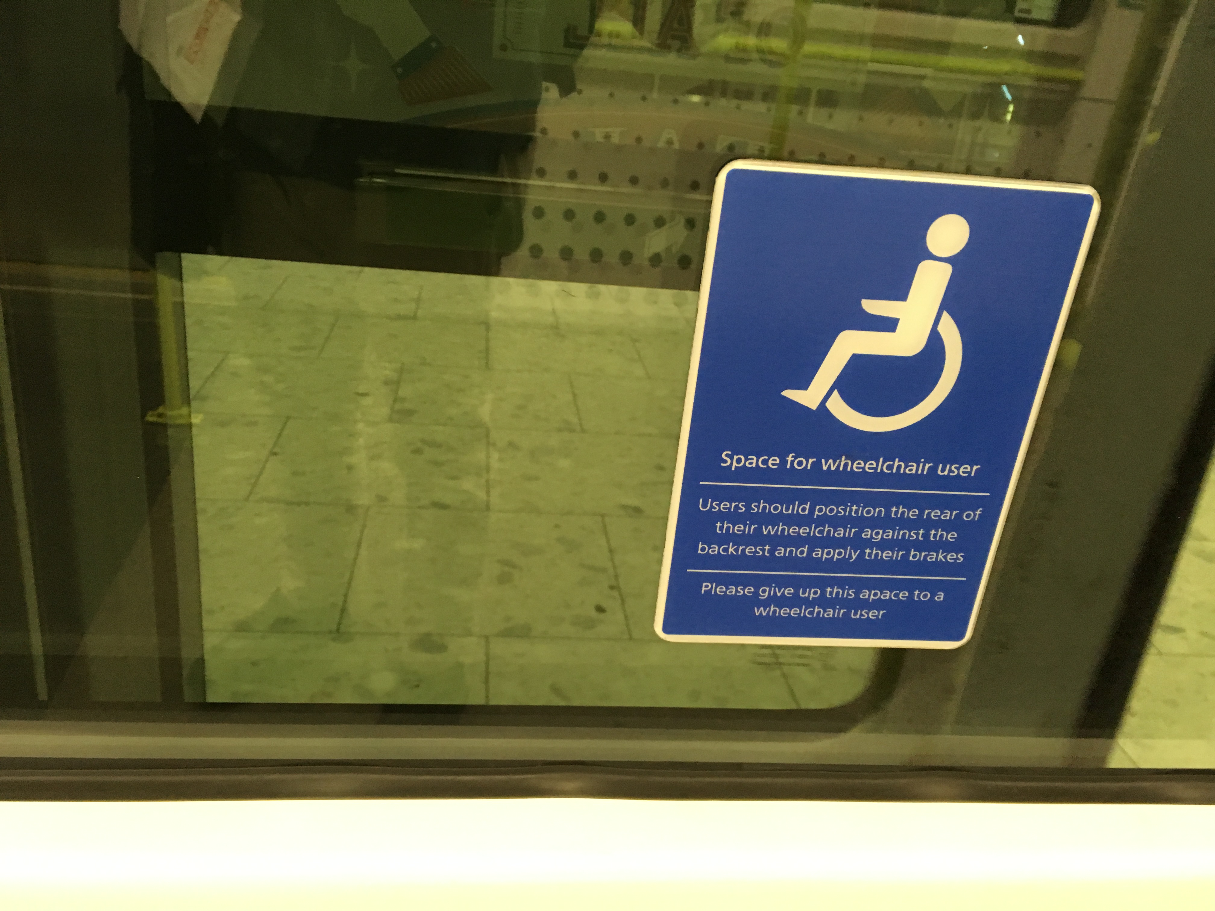 A sign reading Space for wheelchair user beside airport seating.